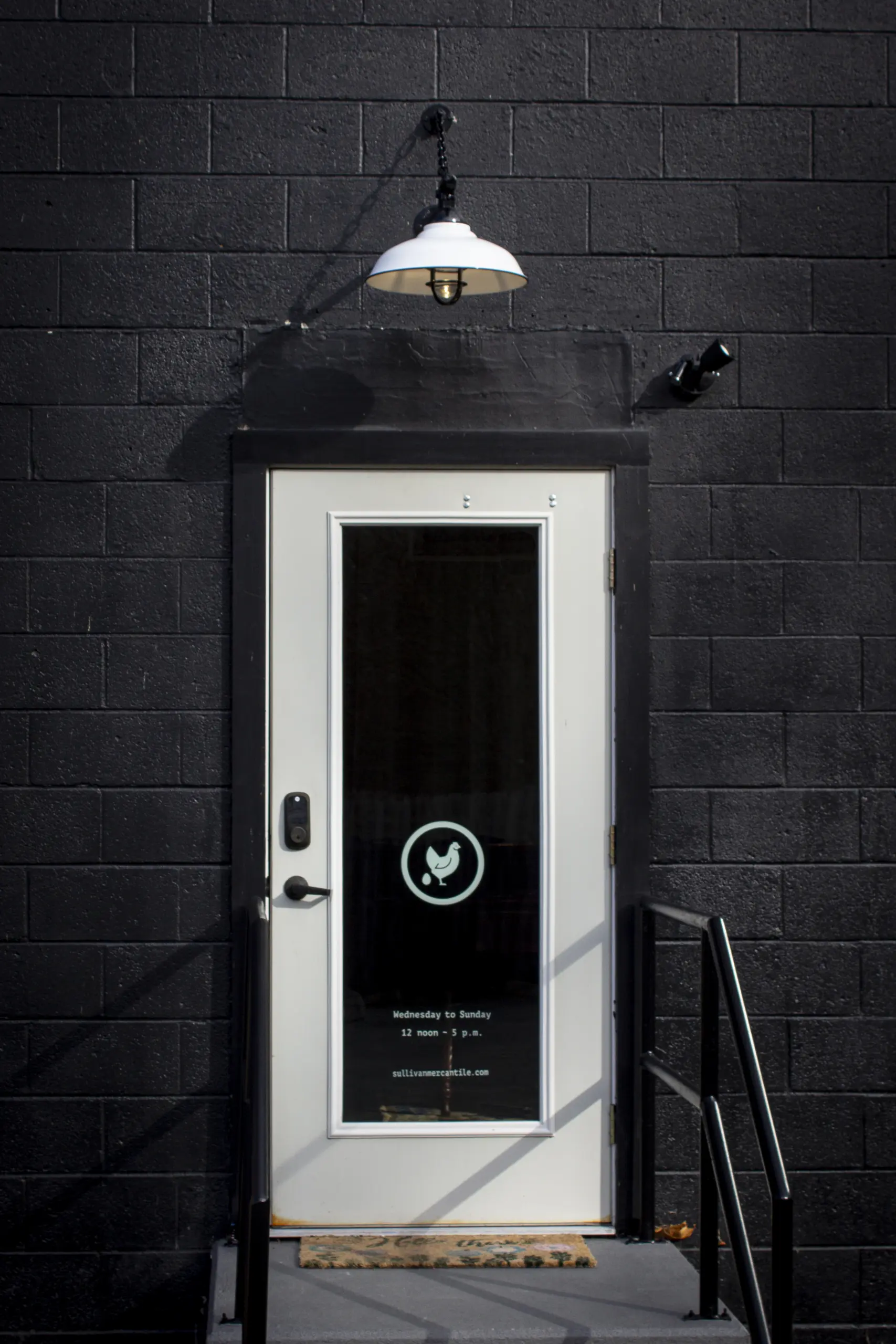 Exterior white door on black building with lamp